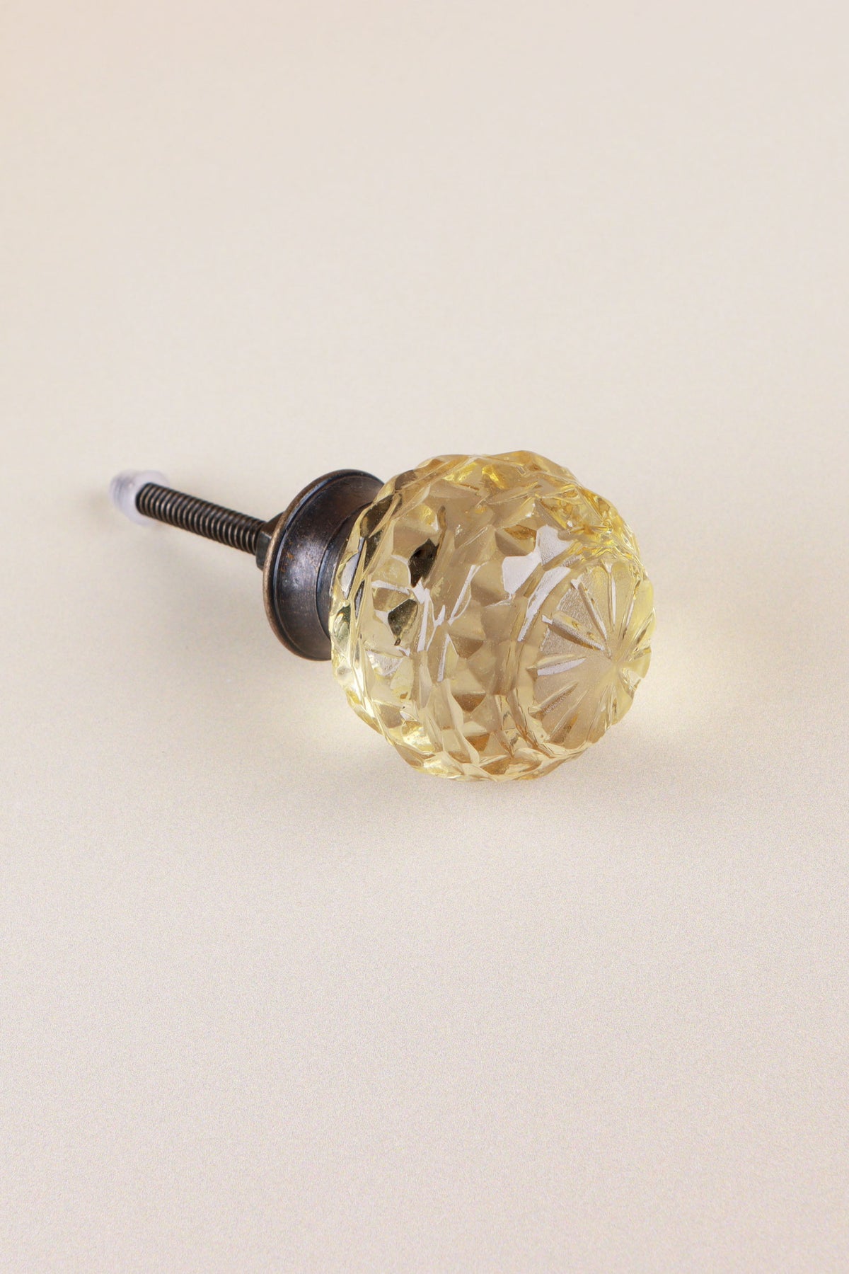 Ivory faceted glass ball cabinet knob, a pale champagne tint, with a star cut on the front, on an antique brass finish base