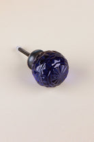 Navy Blue faceted glass ball cabinet knob, a deep inky blue, on an antique brass finish base with its fixing bolt