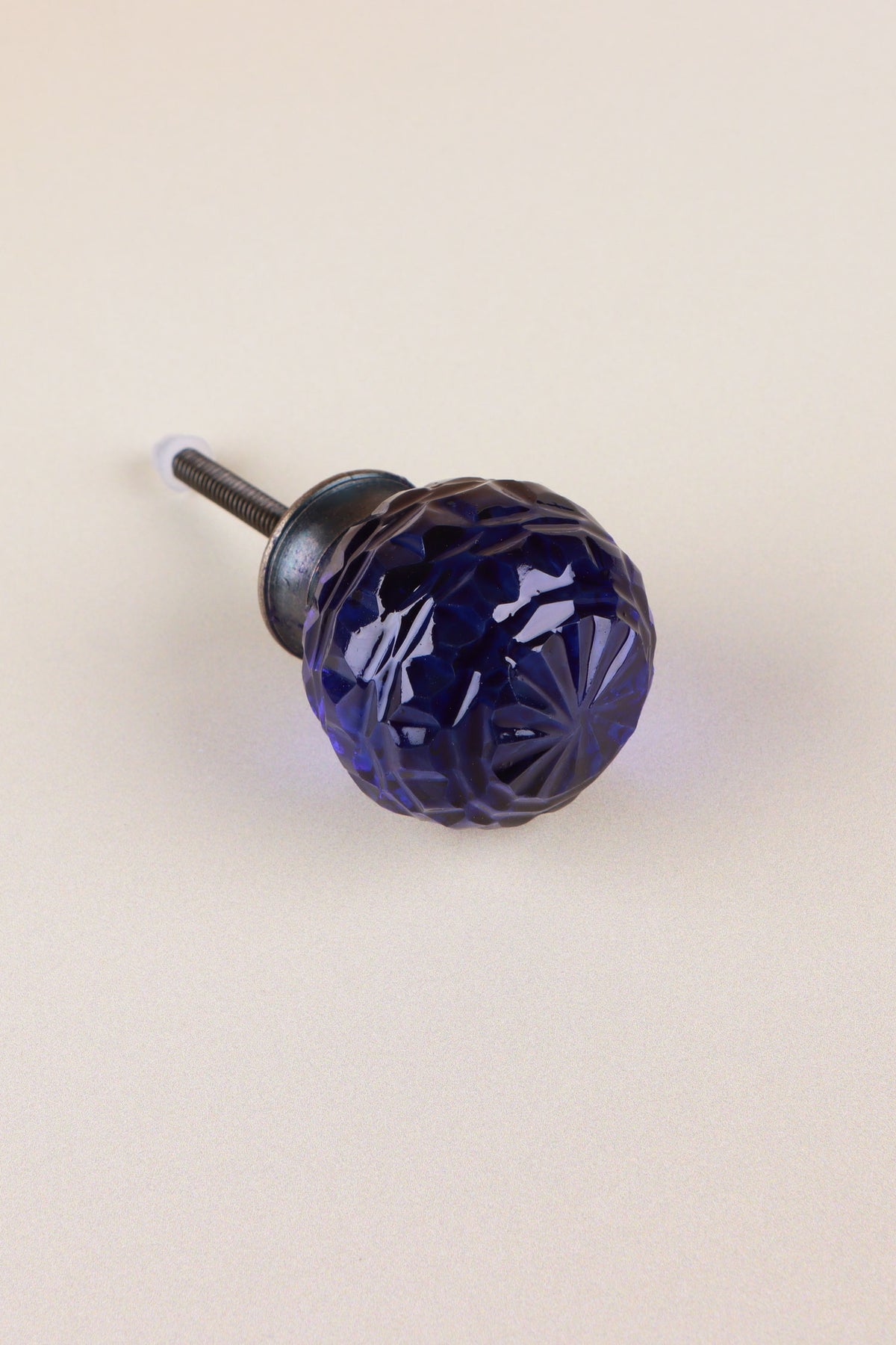 Navy Blue faceted glass ball cabinet knob, a deep inky blue, on an antique brass finish base with its fixing bolt