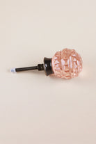 Side view of the blush pink faceted glass knob showing the antique brass finish base, the threaded fixing bolt and two nuts