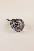 Smokey Grey faceted glass ball cabinet knob with a star cut on the front, on an antique brass finish base with its fixing bolt