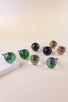 The eight colours of the faceted glass cabinet knob together by a white cupboard door: two greens, smokey grey, navy blue, ivory, blush pink, clear and teal