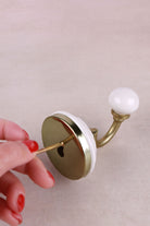 Fixing a floral ceramic wall hook — the screw goes through the centre of the plate