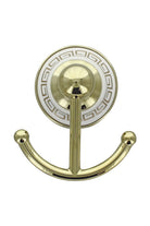Close-up of the gold double robe hook on its white Greek key wall plate