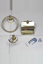 Gold towel ring, toilet roll holder with cover and double robe hook laid on white tiles with the wall plates, screws, wall plugs and Allen key