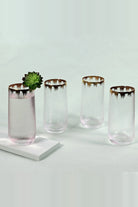Four gold rim hammered glasses, one holding a small succulent on a white stand