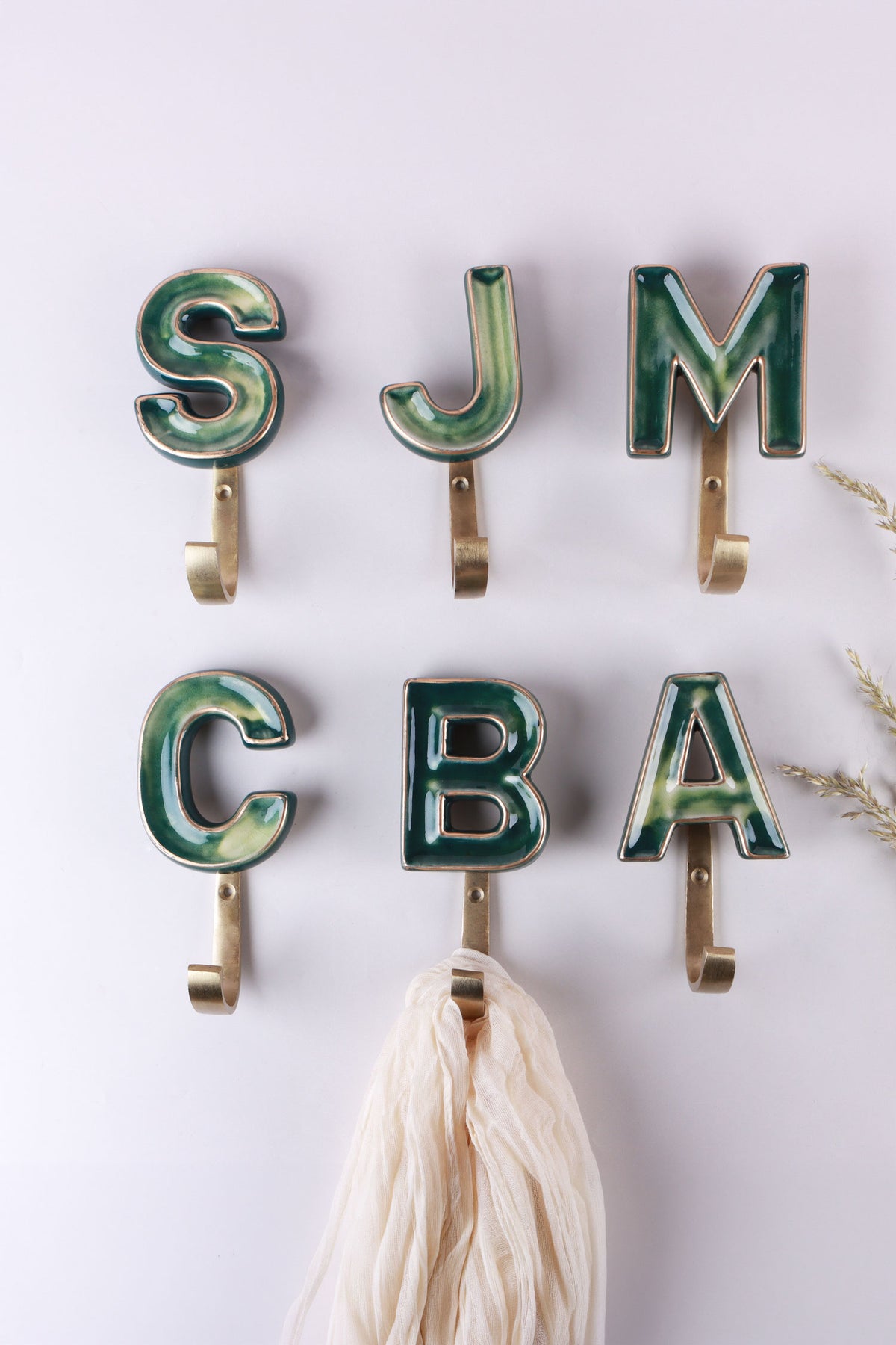 Green ceramic letter hooks on the wall, third view