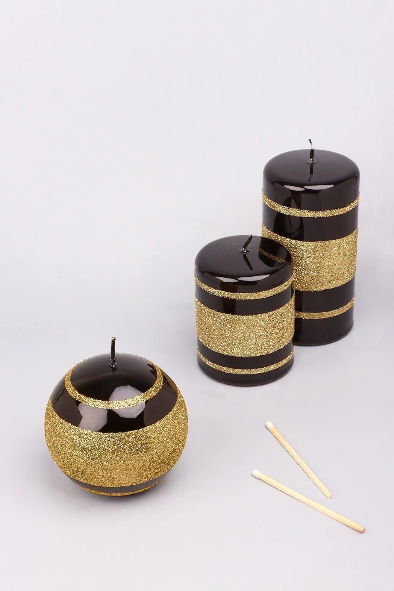 Schwarz-goldene, gestreifte, glitzernde, glänzende Kugel-Stumpenkerzen mit Glaseffekt