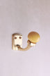 Mustard yellow ceramic ball hook: a mustard yellow ceramic ball on a curved brass-finish hook with a small back plate and two screws