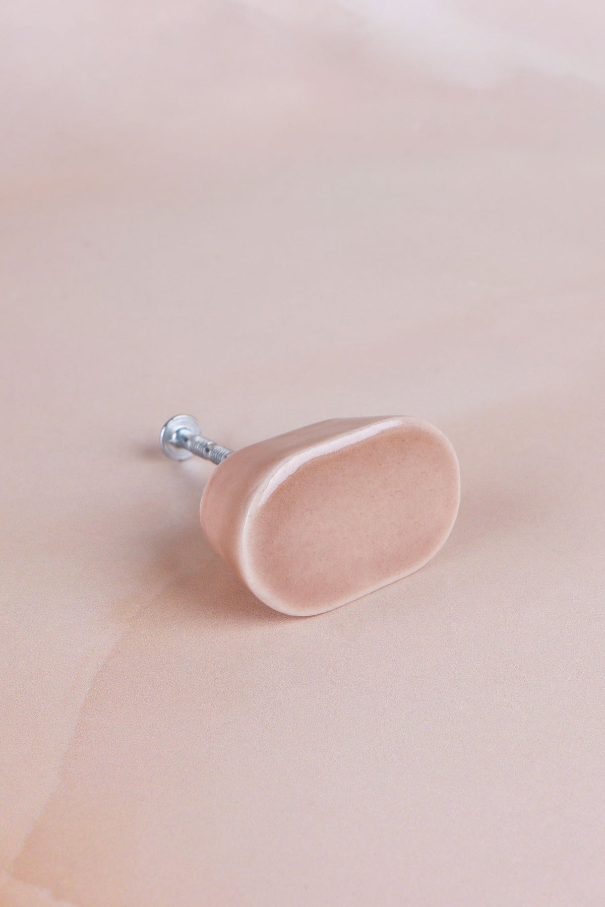Brown oval ceramic cabinet knob, a warm light brown glaze with a fine crackle, with its fixing bolt