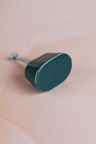 Dark teal oval ceramic cabinet knob, a deep glossy teal green, with its fixing bolt