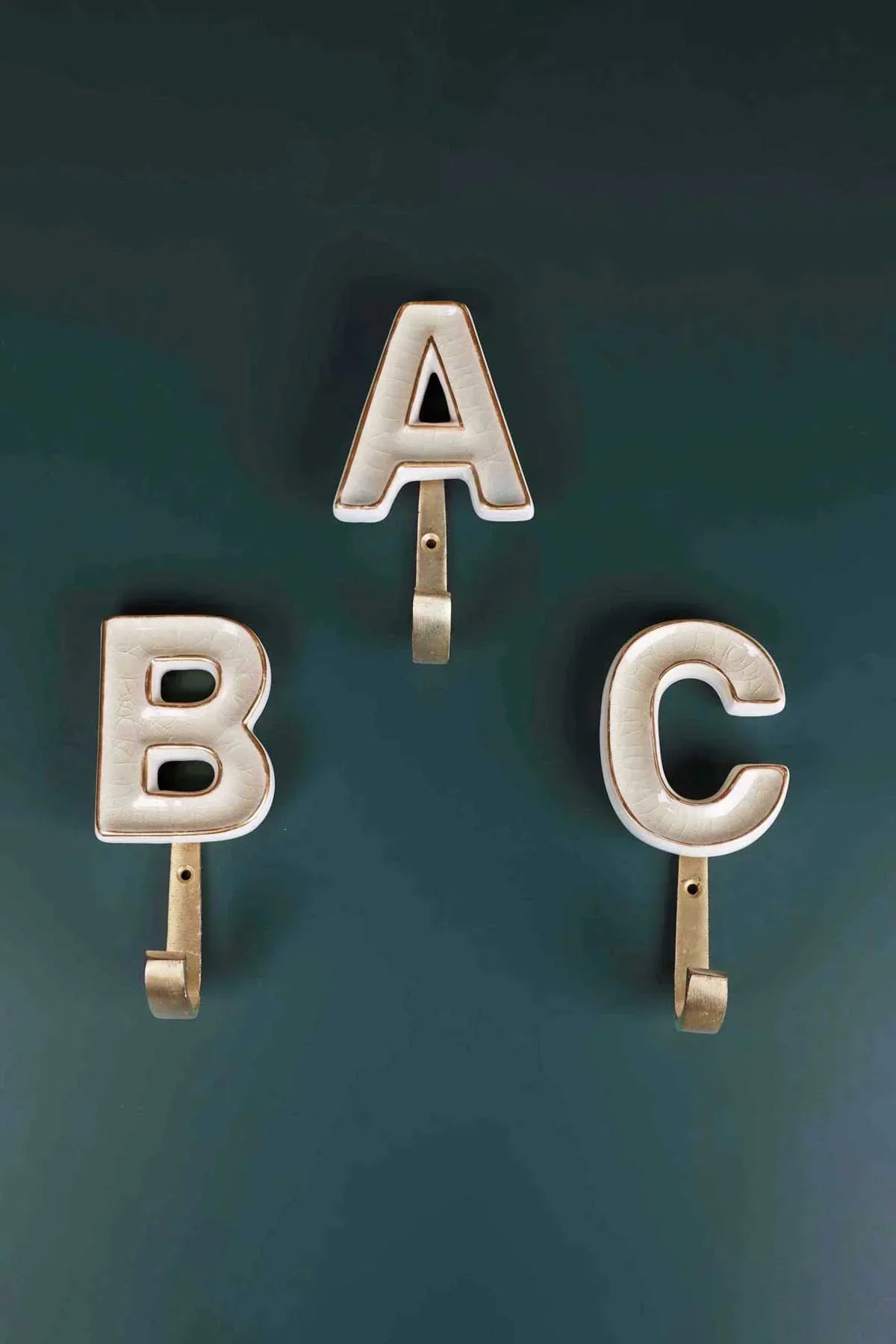 Cream crackle monogram coat hook close-up showing hand-painted ceramic and antique brass alphabet — G Decor