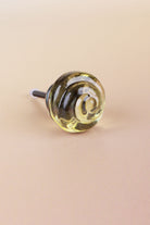 Ivory small rose glass cabinet knob, a pale champagne tint, with a swirl curling into the centre, on an antique brass finish base