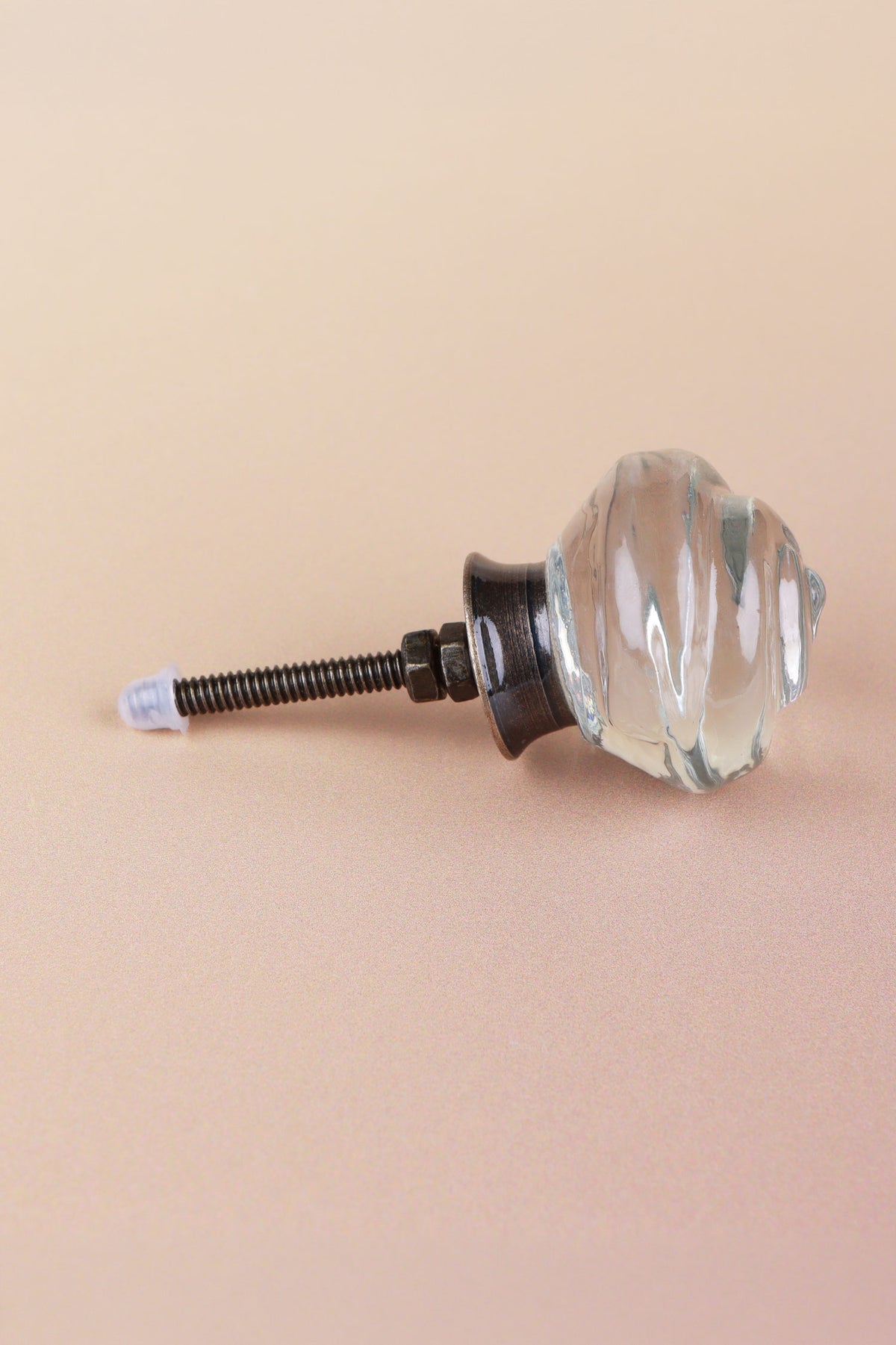 Side view of the clear rose glass knob showing the antique brass finish base, the threaded fixing bolt and two nuts