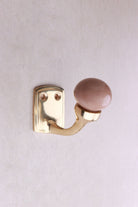 Rosy brown ceramic ball hook: a dusky rose-brown ceramic ball on a curved brass-finish hook with a small back plate and two screws