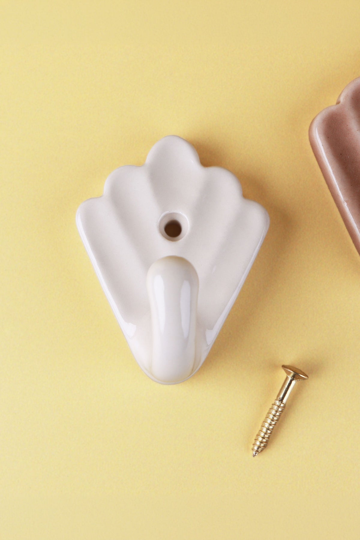 Cream scallop shell ceramic wall hook with its brass screw