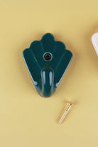 Dark teal scallop shell ceramic wall hook, a deep glossy teal green, with its brass screw