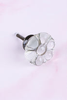 Clear six-petal flower glass cabinet knob on an antique brass finish base with its fixing bolt
