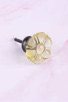 Ivory six-petal flower glass cabinet knob, a pale champagne-yellow tint, on an antique brass finish base