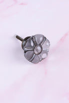Smokey Grey six-petal flower glass cabinet knob, a cool smoked grey, on an antique brass finish base