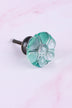 Teal six-petal flower glass cabinet knob, a clear aqua teal, on an antique brass finish base