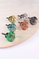 The six colours of the flower glass knob on a wooden board: ivory, clear, smokey grey, teal, blush pink and light green