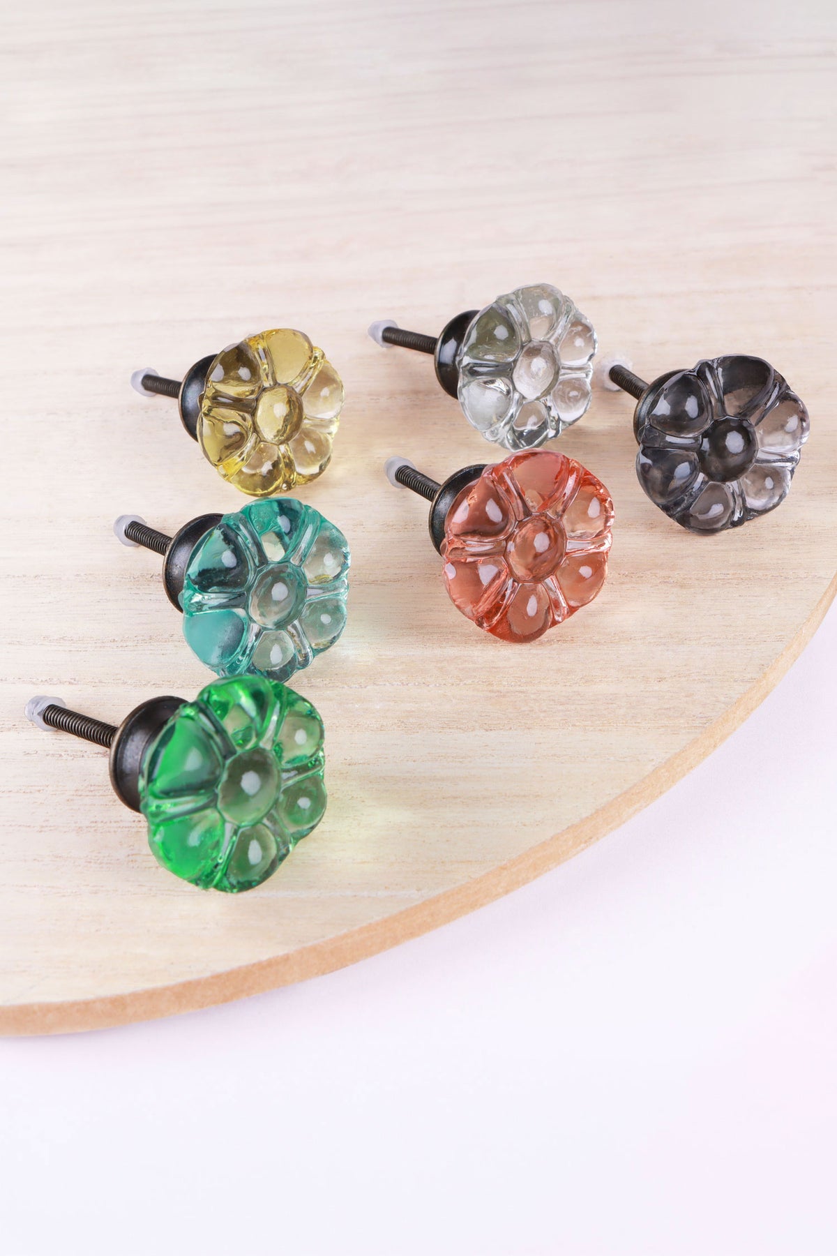 The six colours of the flower glass knob on a wooden board: ivory, clear, smokey grey, teal, blush pink and light green