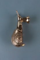 Side view of the brass snail door knocker showing the ribbed spiral shell and the round mount it hangs from