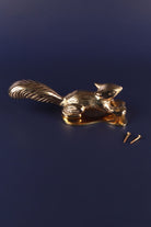 Brass squirrel door knocker on a navy background with its two fixing screws