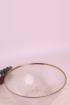 Thalia hammered glass serving bowl with gold rim on a woven placemat with eucalyptus