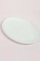 Oval white porcelain shell dish with ridges fanning out from the narrow end