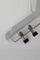 Close-up of a grey wooden clip hanger showing the two metal clips with black tips