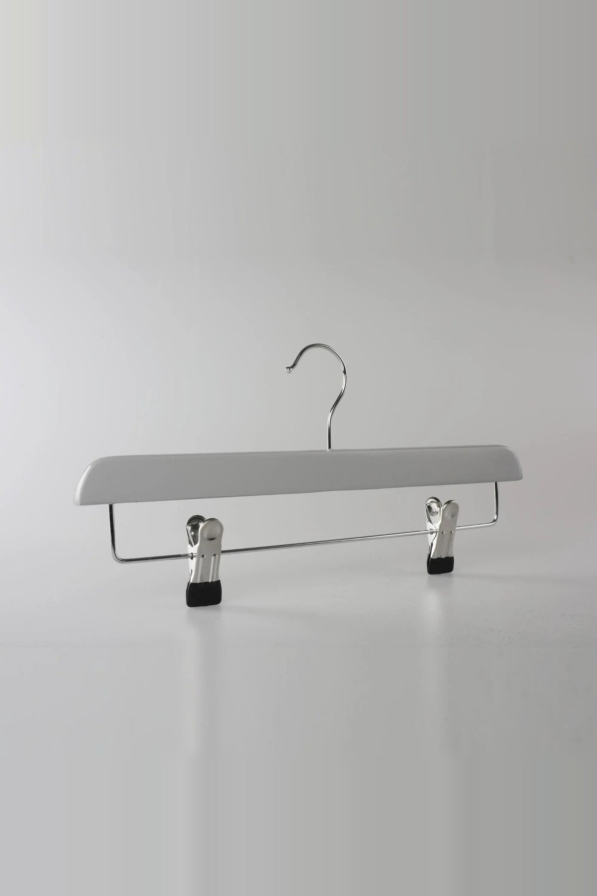 Grey wooden clip hanger with a metal hook and two clips, seen from an angle